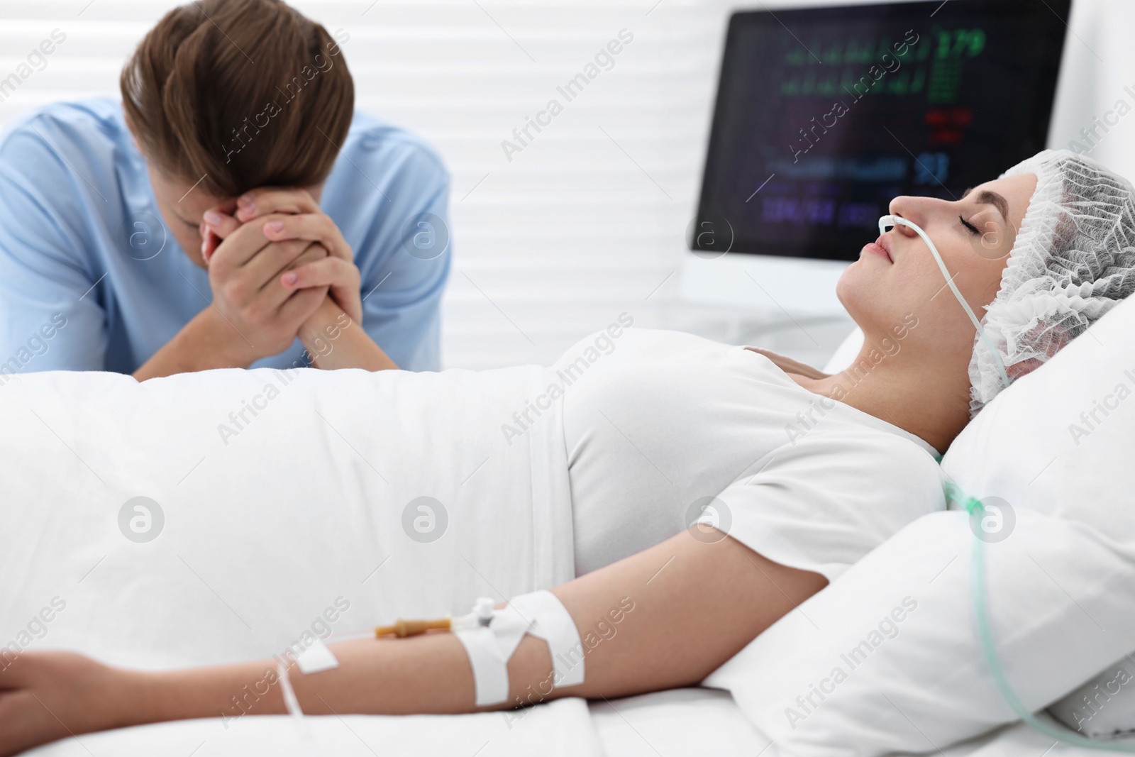 Photo of Coma patient. Sad young man near his unconscious wife in hospital