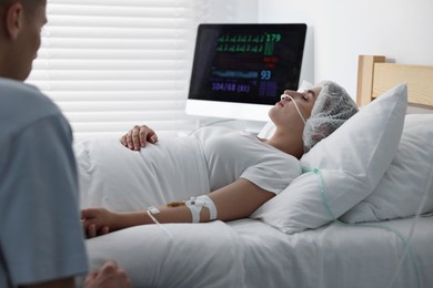 Coma patient. Sad young man near his unconscious wife in hospital