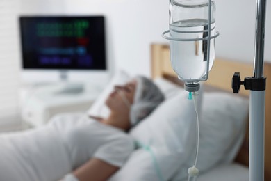 Photo of Coma patient. Young woman with intravenous drip in hospital bed, selective focus