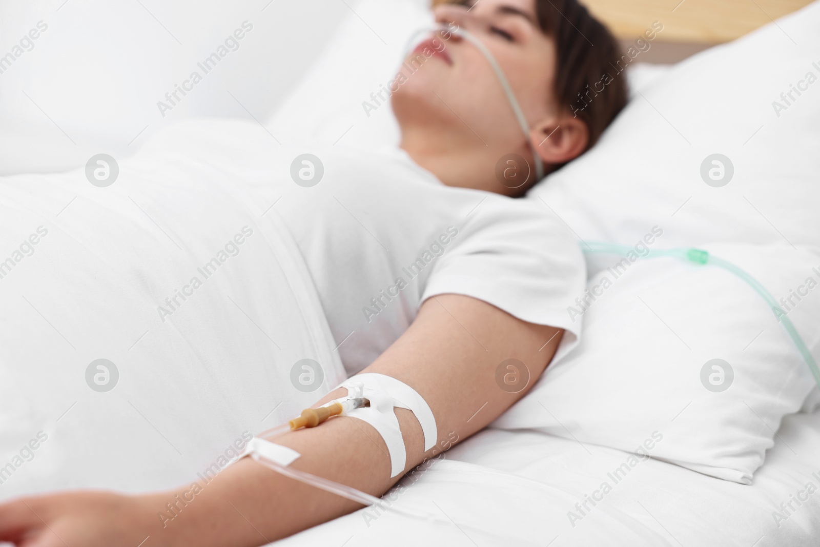 Photo of Coma patient. Young woman with intravenous drip in hospital bed, selective focus