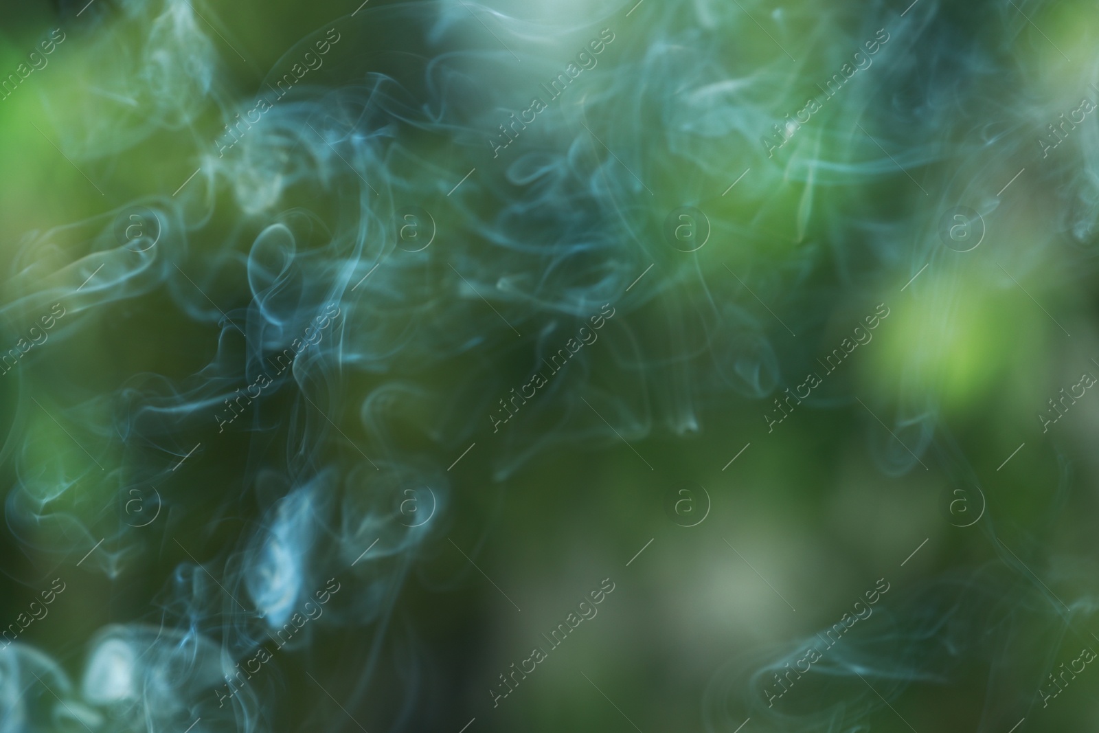 Photo of Smoke from incense stick on green blurred background