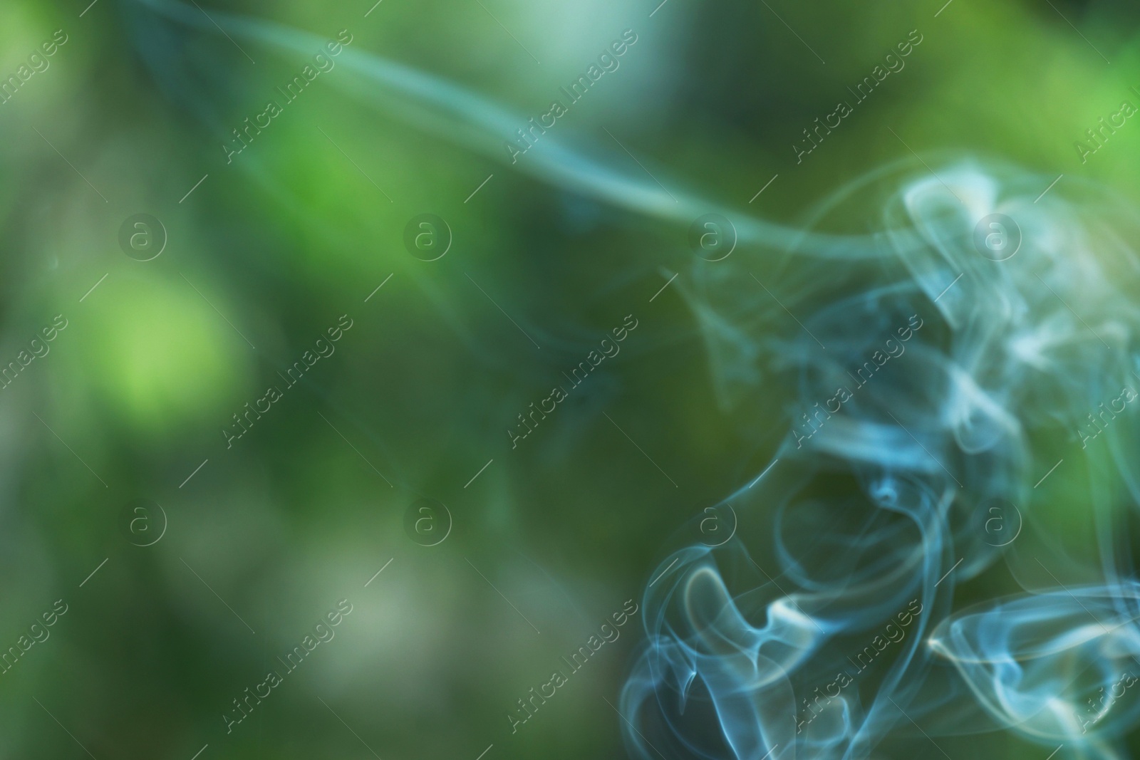 Photo of Smoke from incense stick on green blurred background, space for text