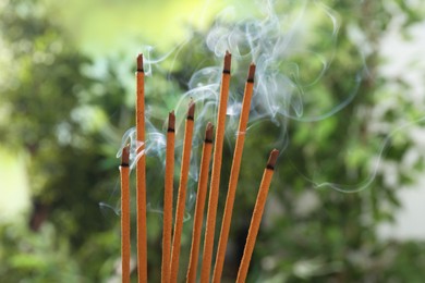 Incense sticks smoldering on green blurred background