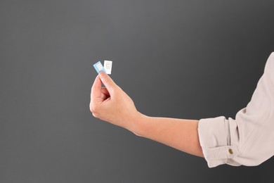 Photo of Woman holding SIM cards on dark grey background, closeup