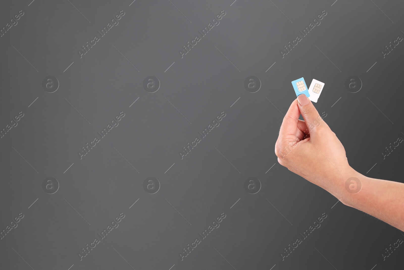 Photo of Woman holding SIM cards on dark grey background, closeup. Space for text