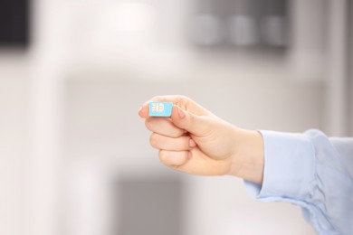 Photo of Woman holding SIM card indoors, closeup. Space for text