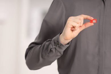 Photo of Woman holding modern SIM card indoors, closeup