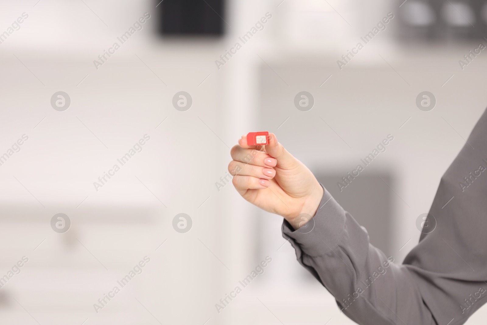 Photo of Woman holding SIM card indoors, closeup. Space for text