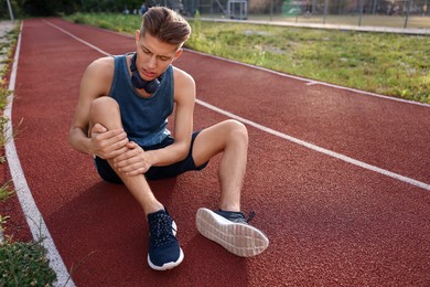 Sportsman with leg injury at stadium, space for text