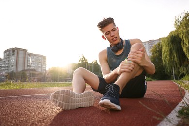 Sportsman with leg injury at stadium, space for text