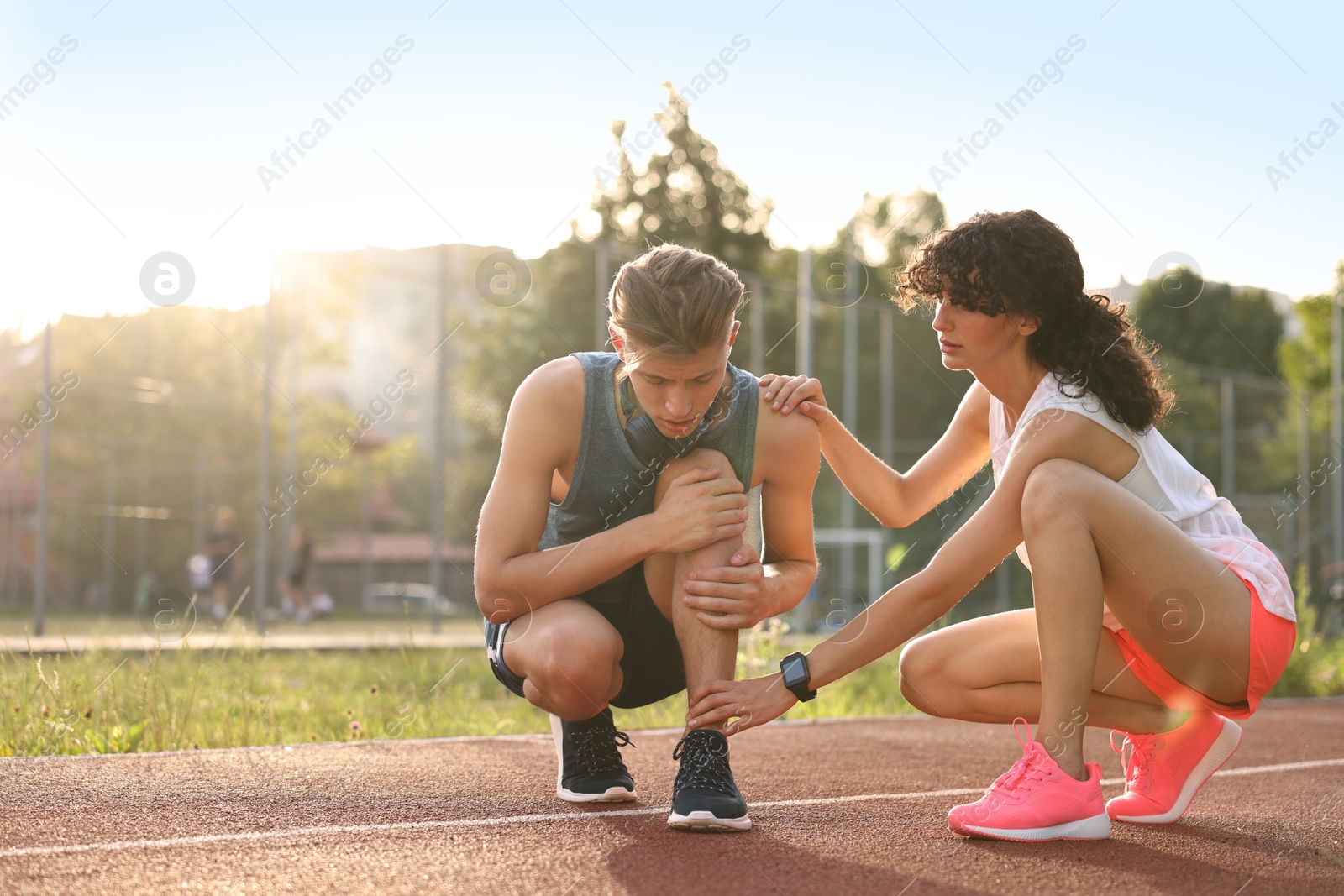 Photo of Sports injury. Woman helping man with leg pain at stadium, space for text