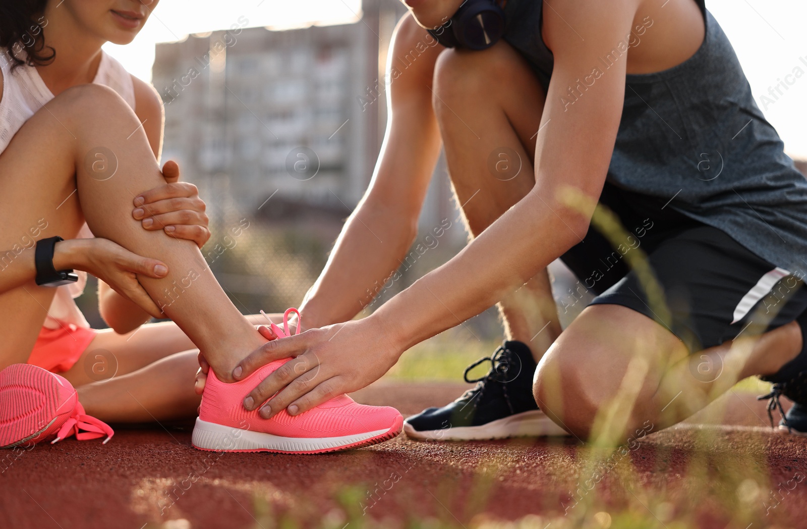 Photo of Sports injury. Man helping woman with leg pain at stadium, closeup