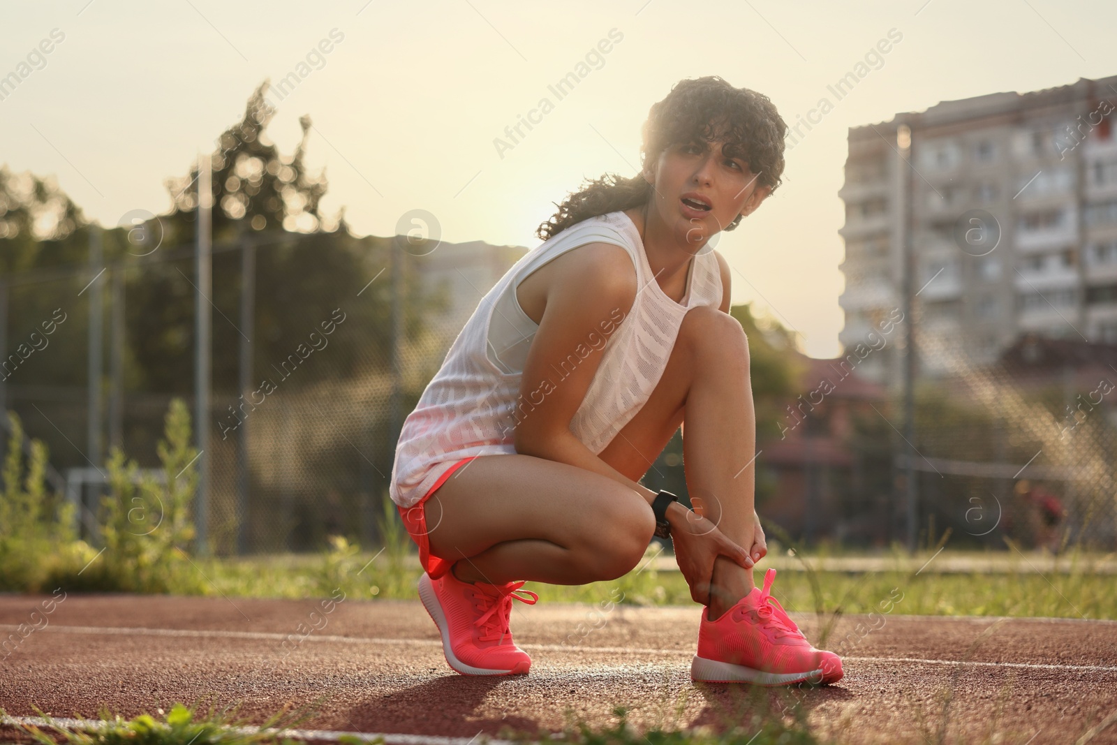 Photo of Sports injury. Woman suffering from leg pain at stadium