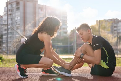 Sports injury. Woman helping man with leg pain at stadium