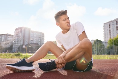 Sports injury. Man suffering from leg pain at stadium