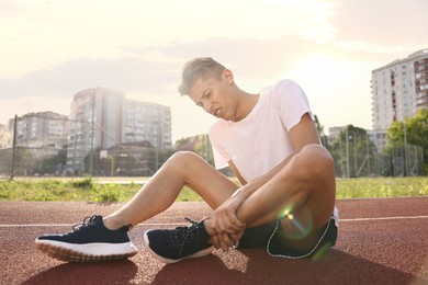 Sports injury. Man suffering from leg pain at stadium