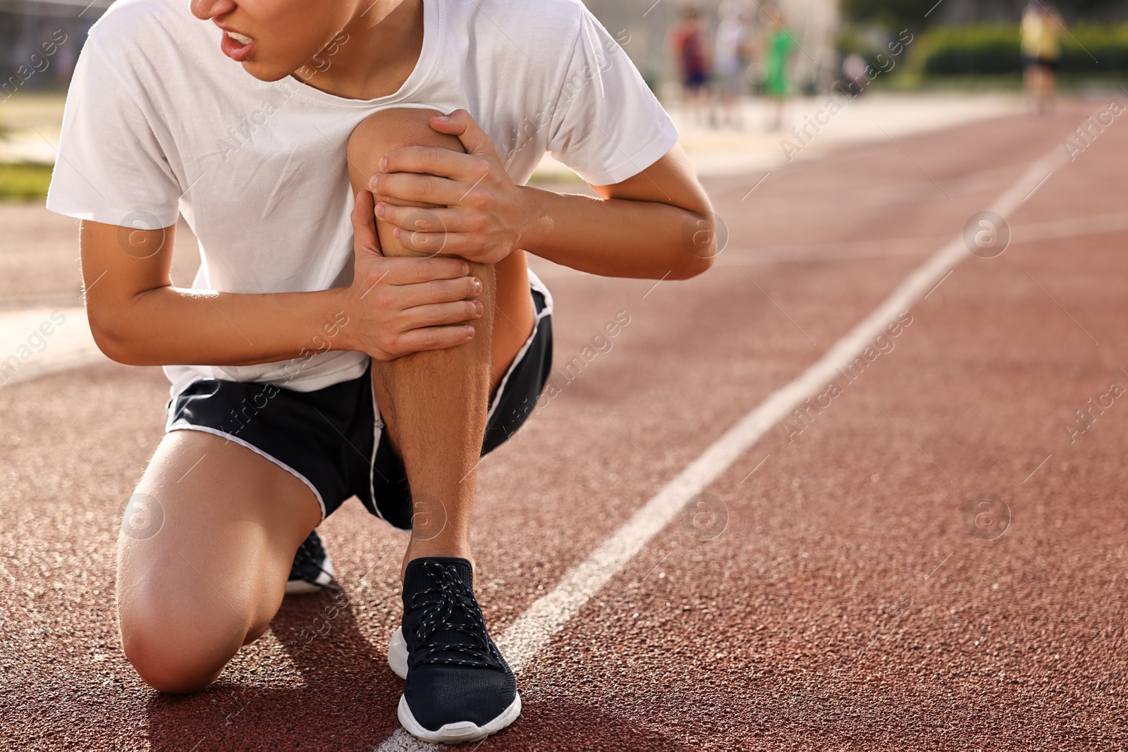 Photo of Sportsman with leg injury suffering from knee pain at stadium, closeup. Space for text