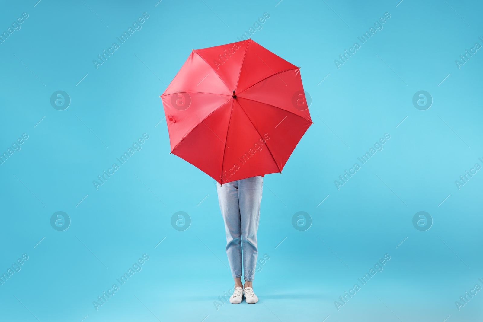 Photo of Woman with red umbrella on light blue background