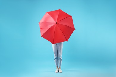 Woman with red umbrella on light blue background