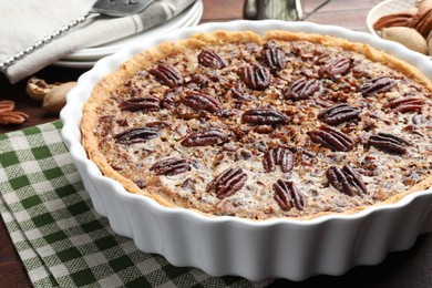 Delicious pecan pie in baking dish on table, closeup