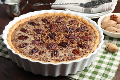 Photo of Delicious pecan pie in baking dish on table, closeup