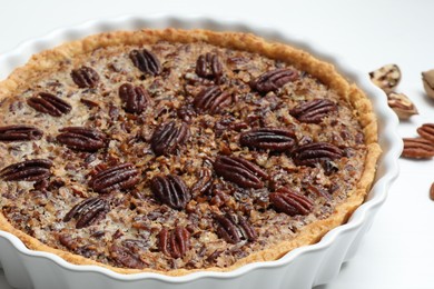 Photo of Delicious pecan pie in baking dish on table, closeup