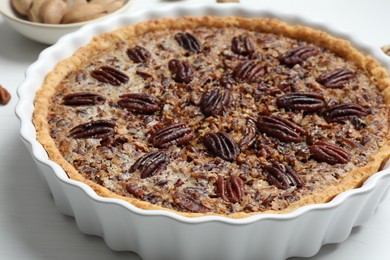 Photo of Delicious pecan pie in baking dish on table, closeup