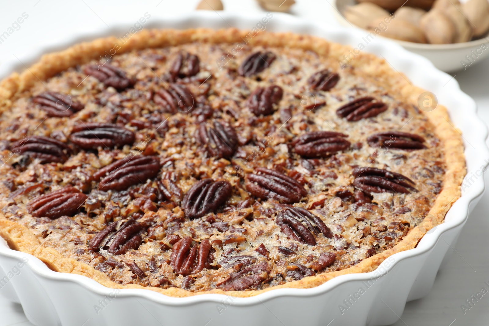 Photo of Delicious pecan pie in baking dish on table, closeup