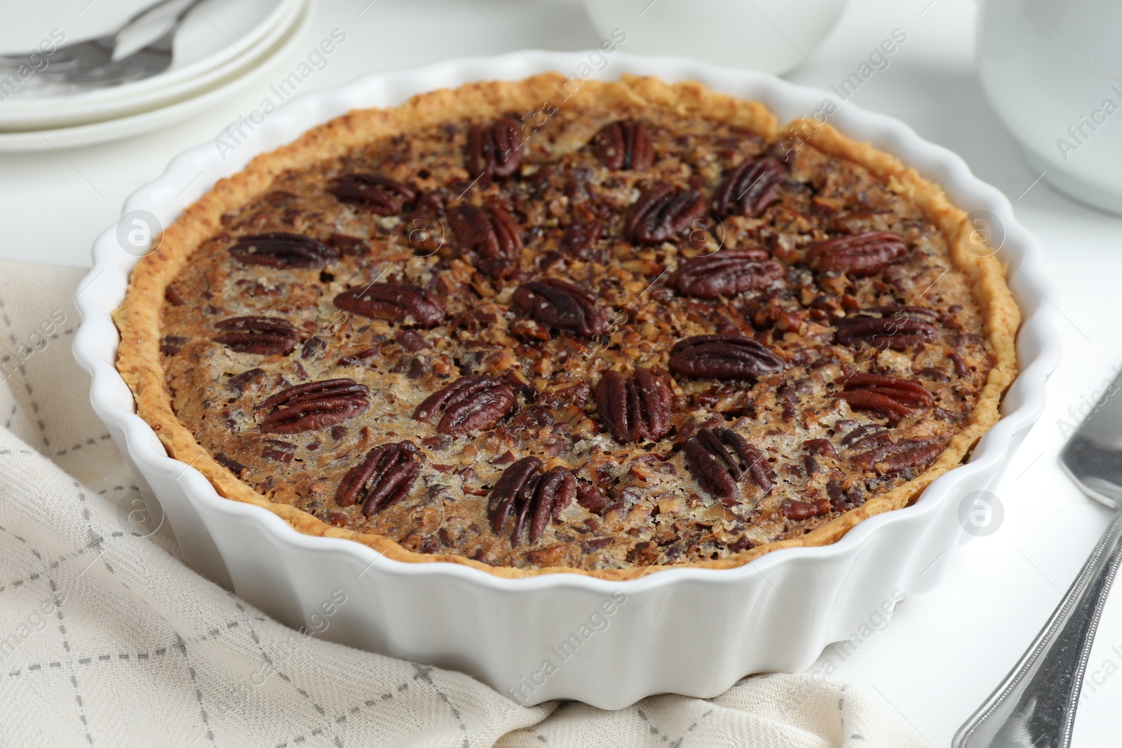 Photo of Delicious pecan pie in baking dish on table, closeup