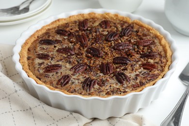 Photo of Delicious pecan pie in baking dish on table, closeup