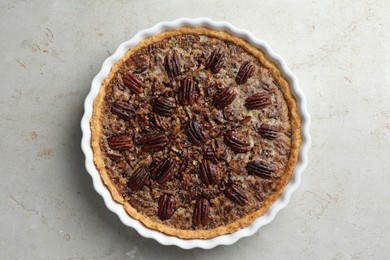 Photo of Delicious pecan pie in baking dish on gray table, top view