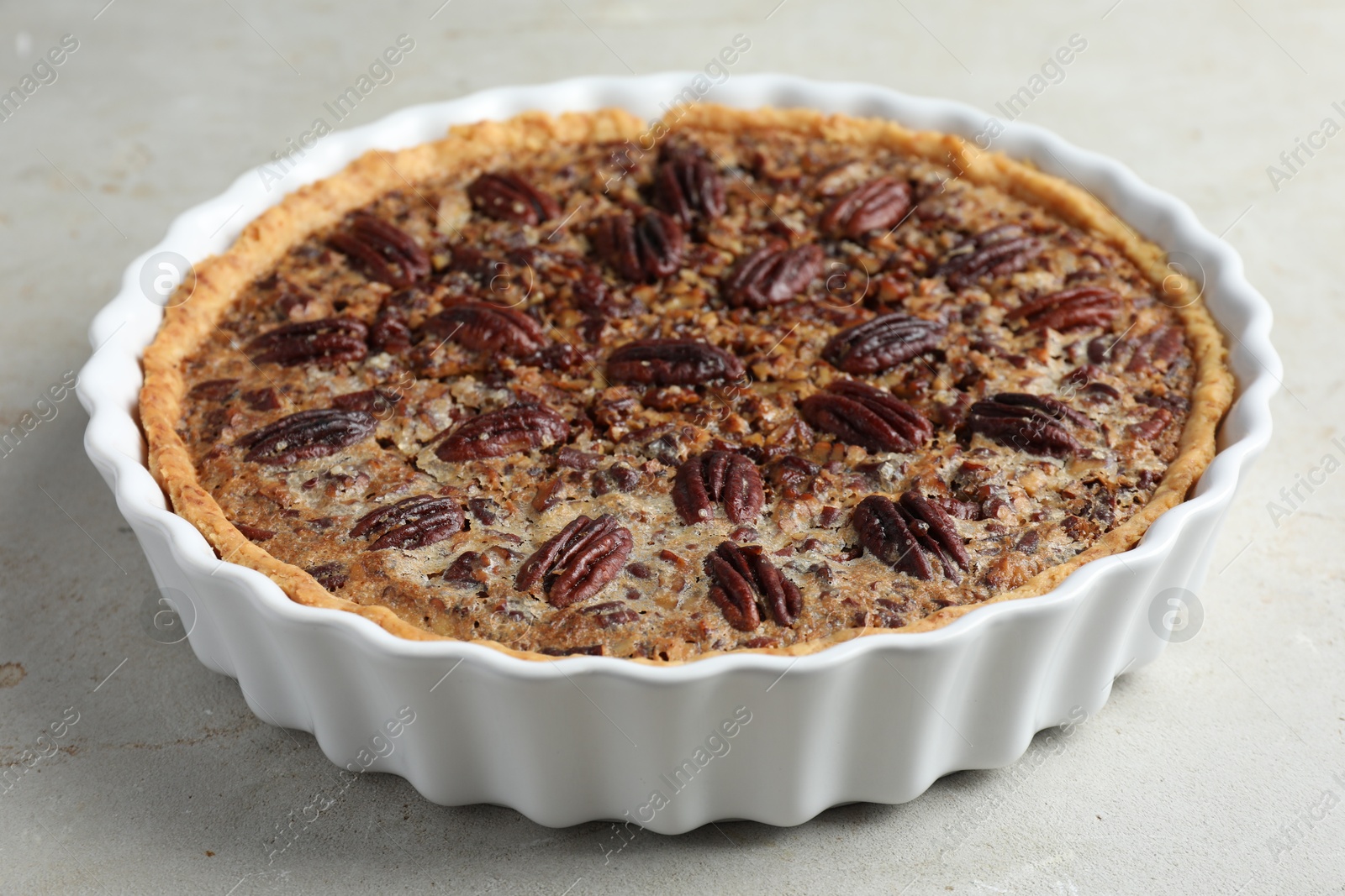 Photo of Delicious pecan pie in baking dish on gray table, closeup