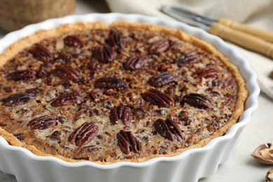 Delicious pecan pie in baking dish on table, closeup