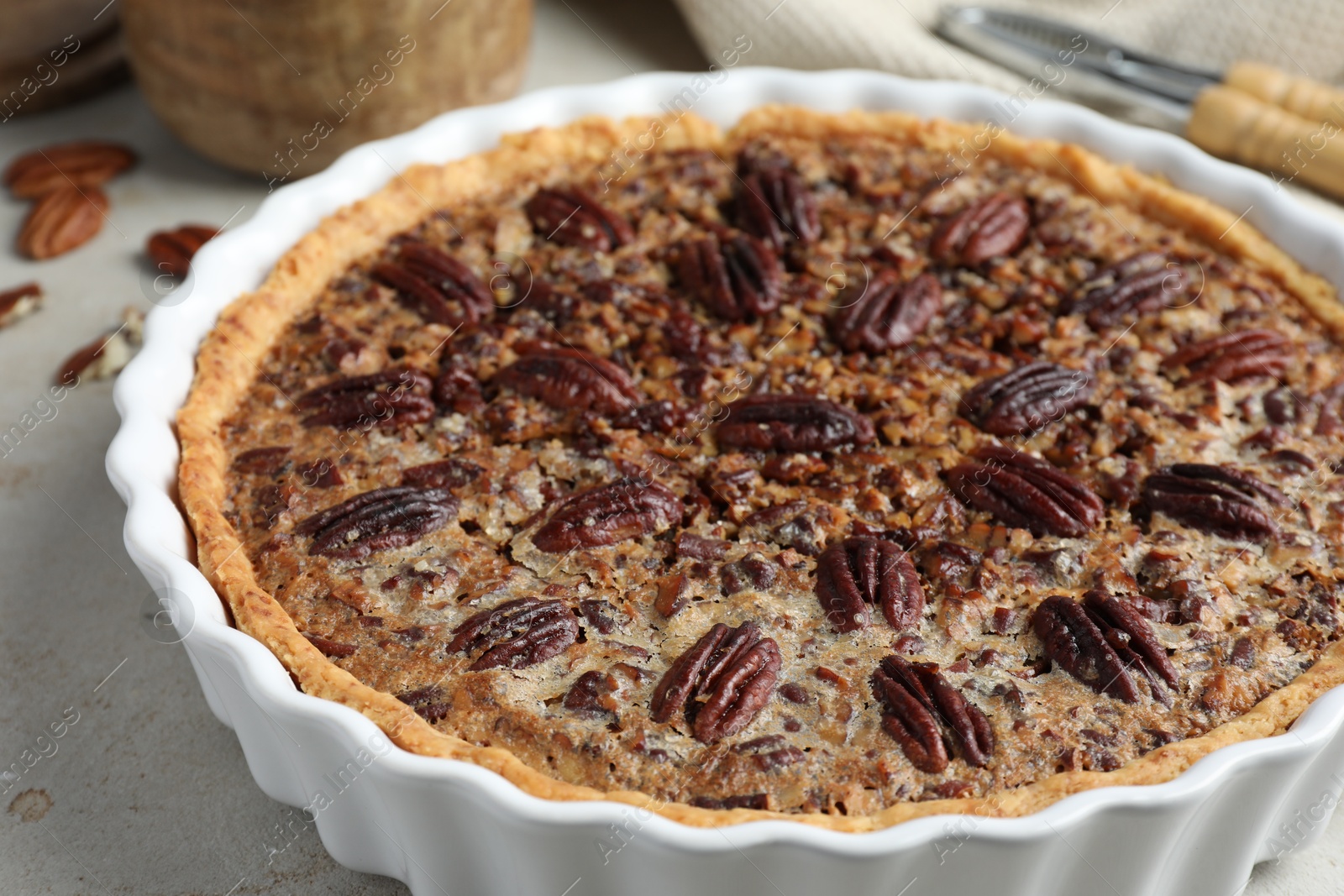 Photo of Delicious pecan pie in baking dish on gray table, closeup