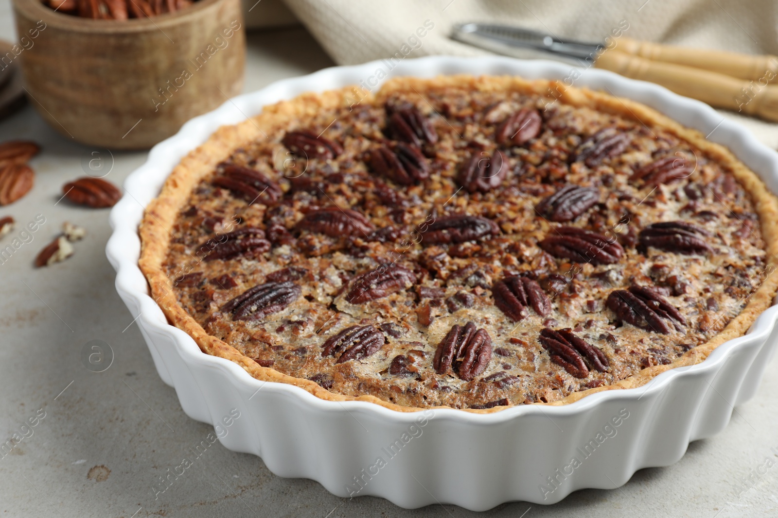 Photo of Delicious pecan pie in baking dish on gray table, closeup