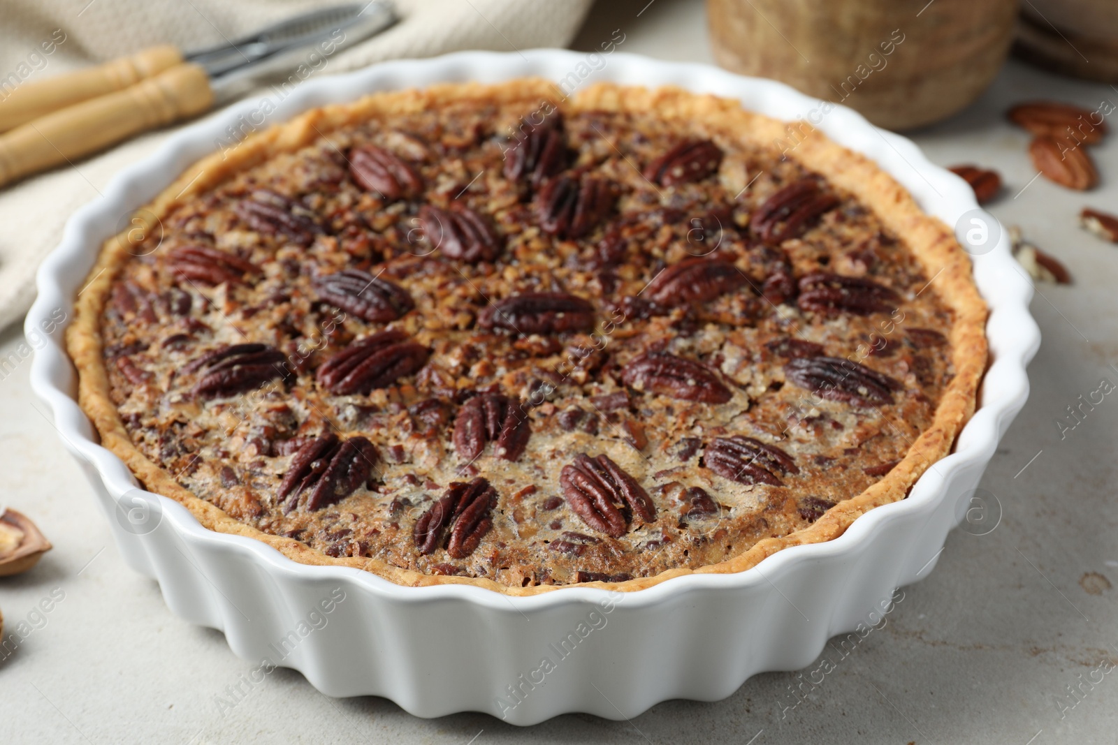 Photo of Delicious pecan pie in baking dish on gray table, closeup