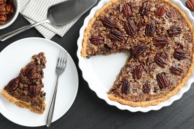 Photo of Delicious pecan pie, fresh nuts and cake server on dark gray textured table, top view