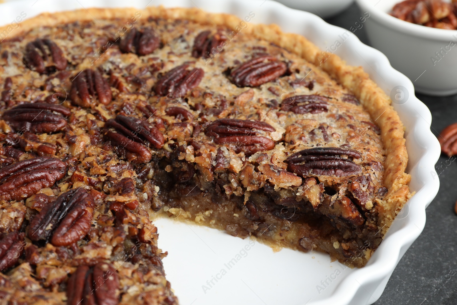 Photo of Delicious pecan pie in baking dish on table, closeup