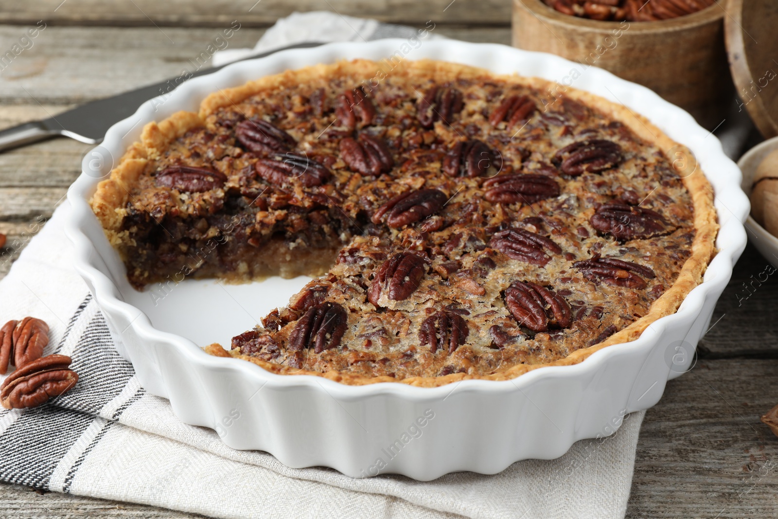 Photo of Delicious pecan pie in baking dish on wooden table, closeup