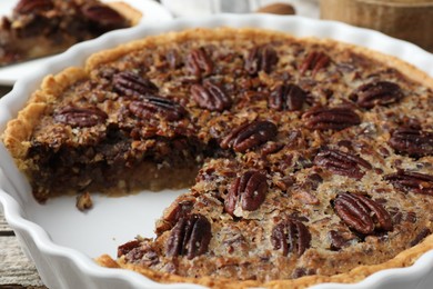 Photo of Delicious pecan pie in baking dish on table, closeup