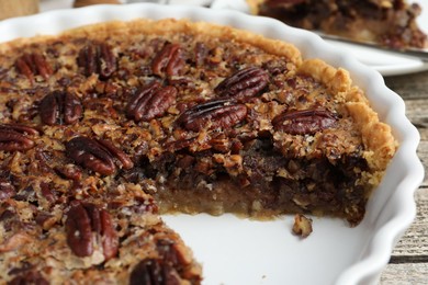 Photo of Delicious pecan pie in baking dish on table, closeup