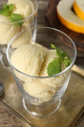 Photo of Scoops of melon sorbet and mint in glass dessert bowls on table, closeup