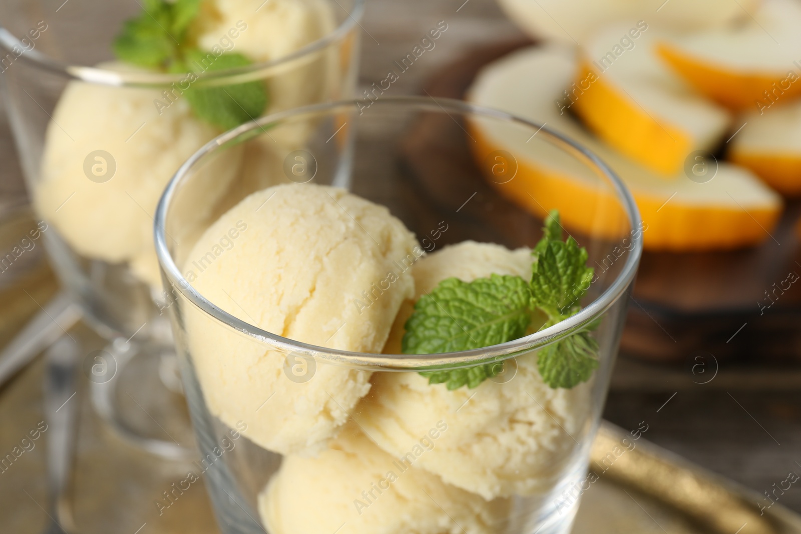 Photo of Scoops of melon sorbet and mint in glass dessert bowls on table, closeup