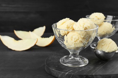 Scoops of melon sorbet in glass dessert bowls on dark wooden table