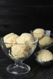 Photo of Scoops of melon sorbet in glass dessert bowls on dark table, closeup