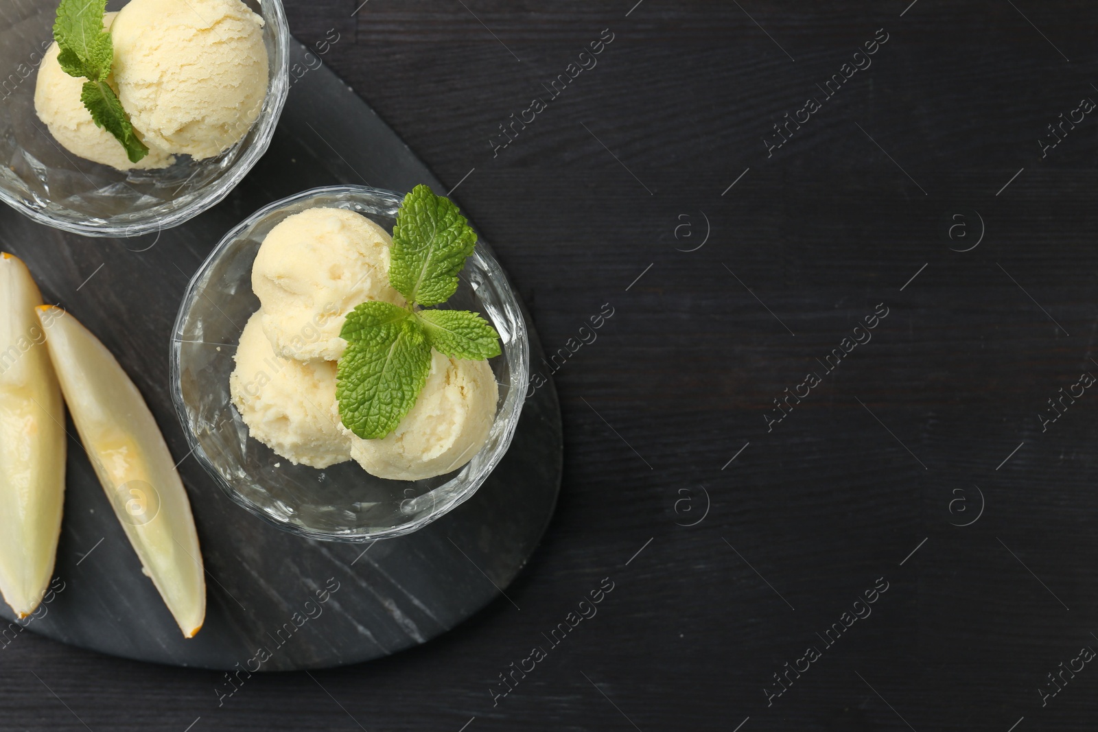 Photo of Scoops of melon sorbet with mint in glass dessert bowls and fresh fruit on dark wooden table, flat lay. Space for text