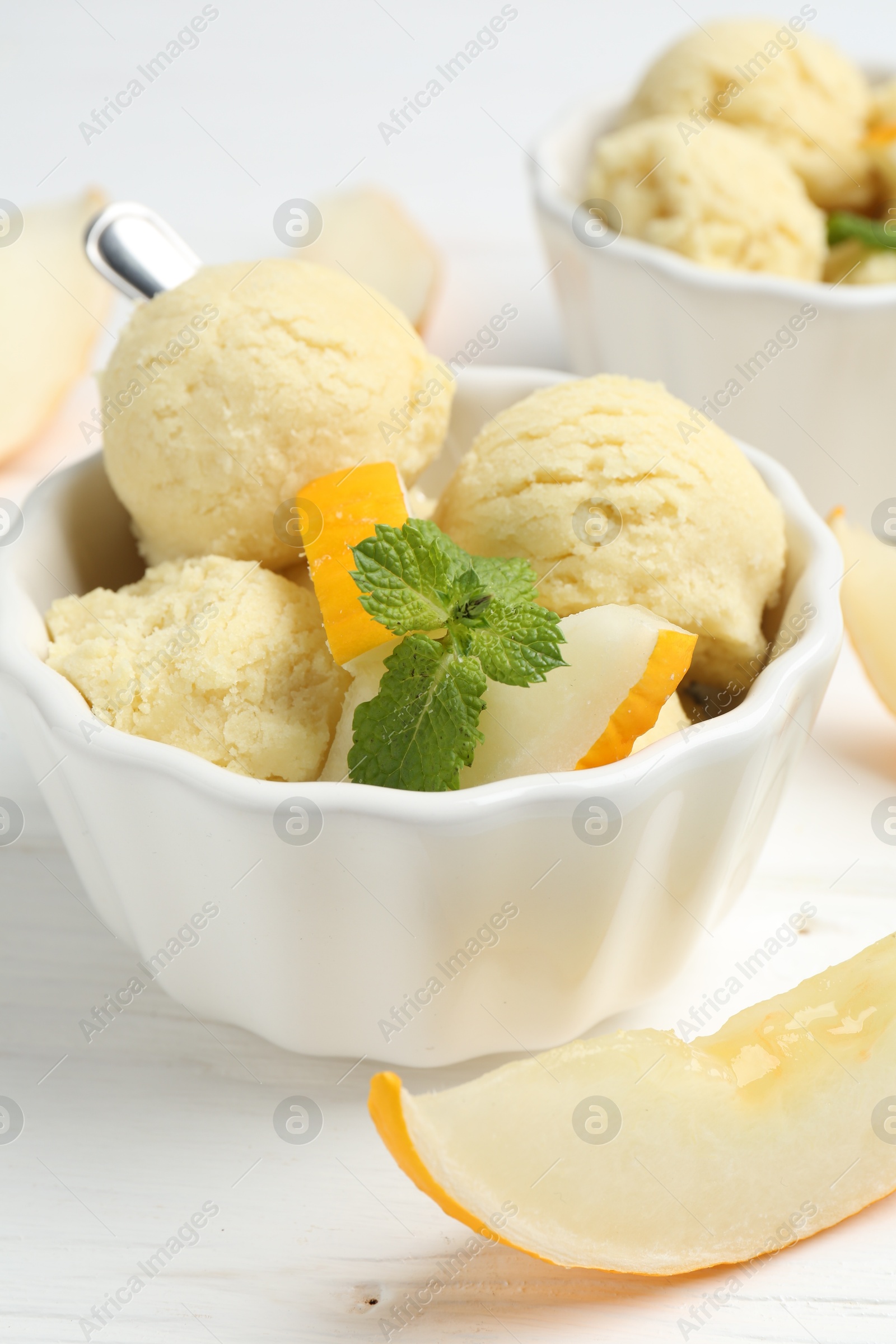 Photo of Scoops of melon sorbet with mint and fresh fruit in bowls on white wooden table, closeup