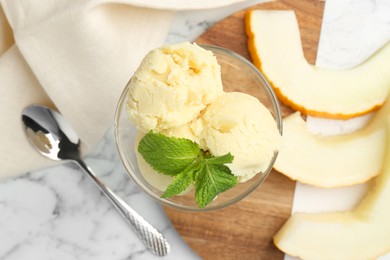 Photo of Scoops of melon sorbet with mint in glass dessert bowl and fresh fruit on light marble table, flat lay