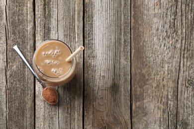 Photo of Delicious protein shake in glass and spoon with powder on wooden table, top view. Space for text