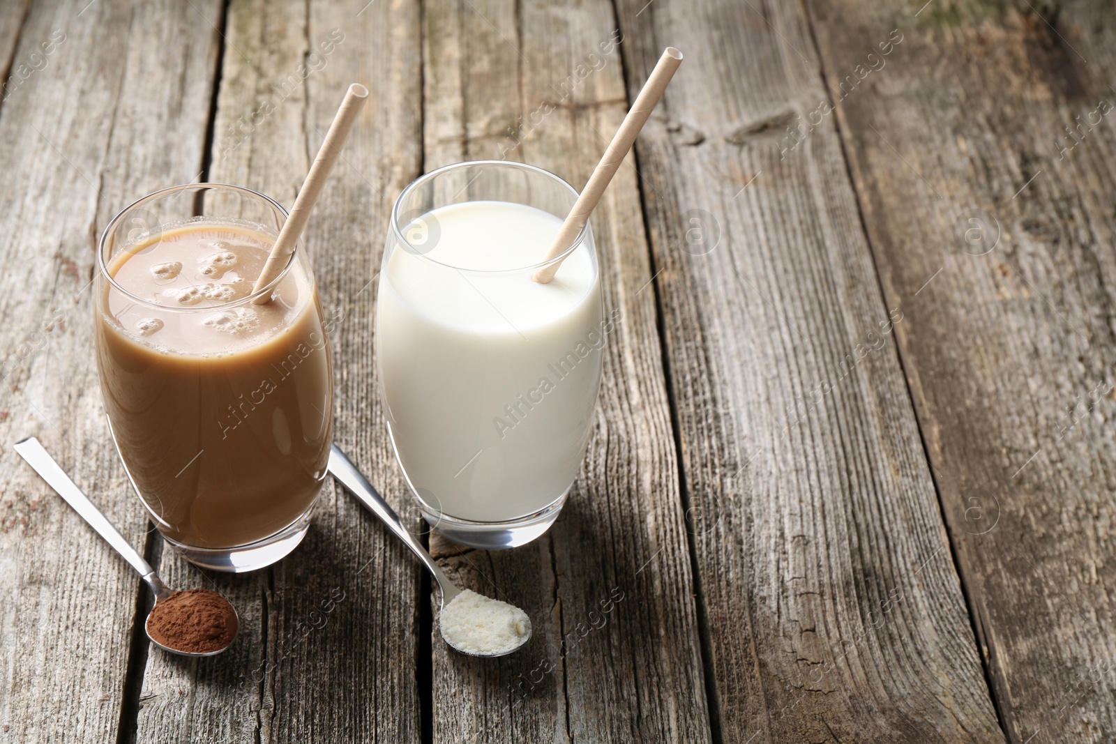 Photo of Delicious protein shakes in glasses and spoons with powder on wooden table, space for text